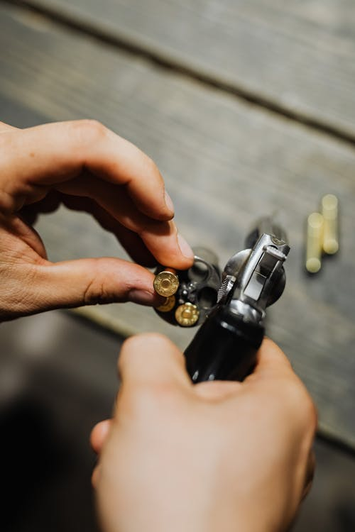 A person loading a revolver with bullets