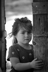A child with her hand on a wooden gate