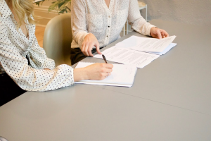 A couple of women sitting at a desk going through documents