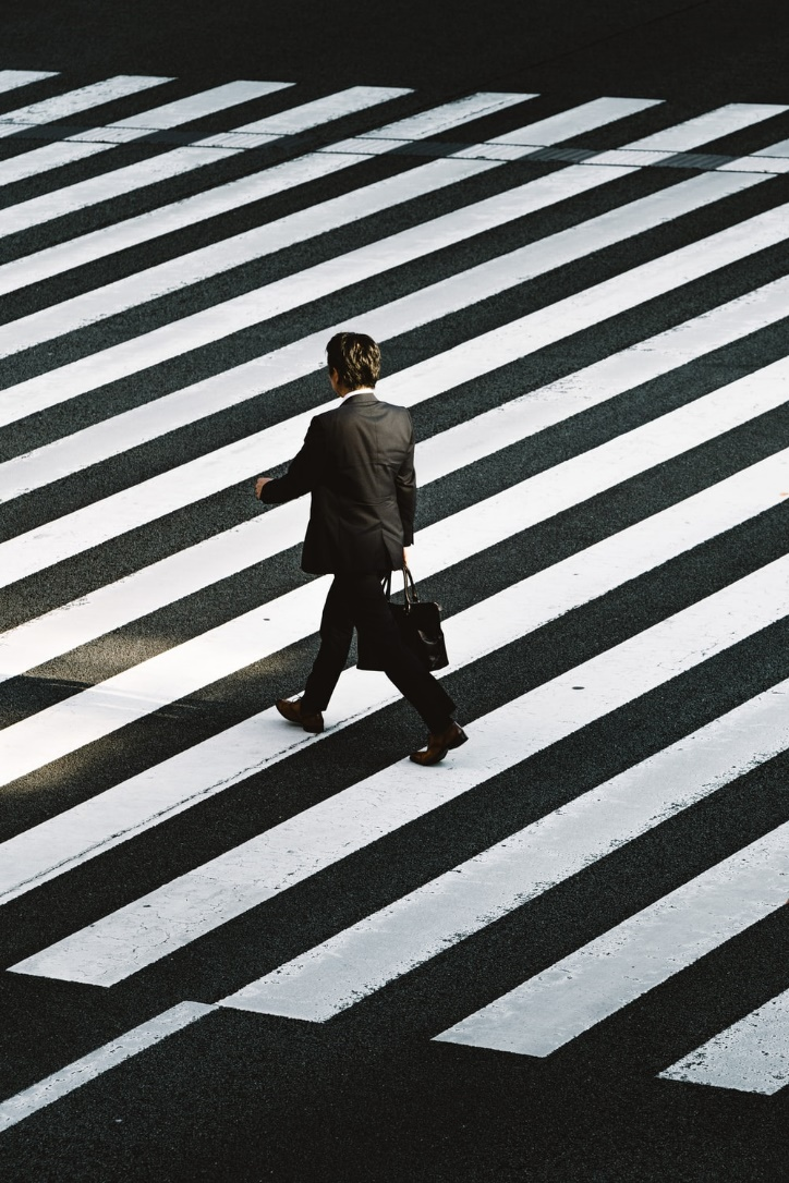A man in a suit walking along a zebra crossing