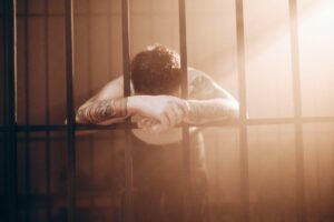 An incarcerated man leaning on prison bars