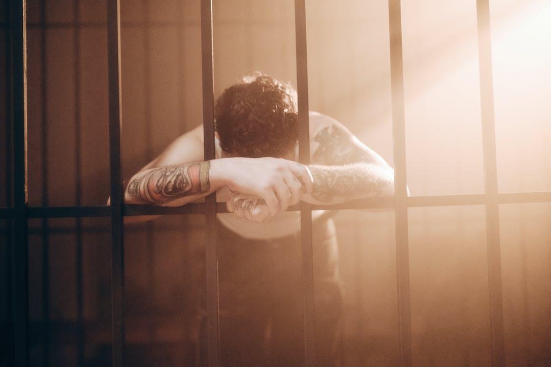 An incarcerated man leaning on prison bars
