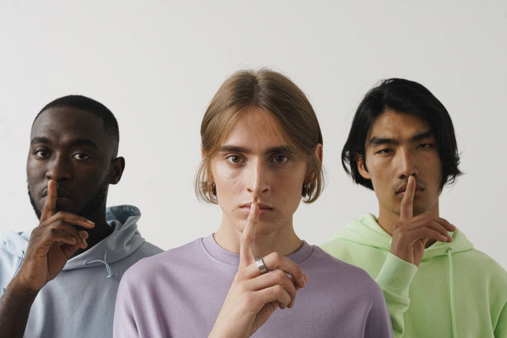 Three people with their fingers on their mouth