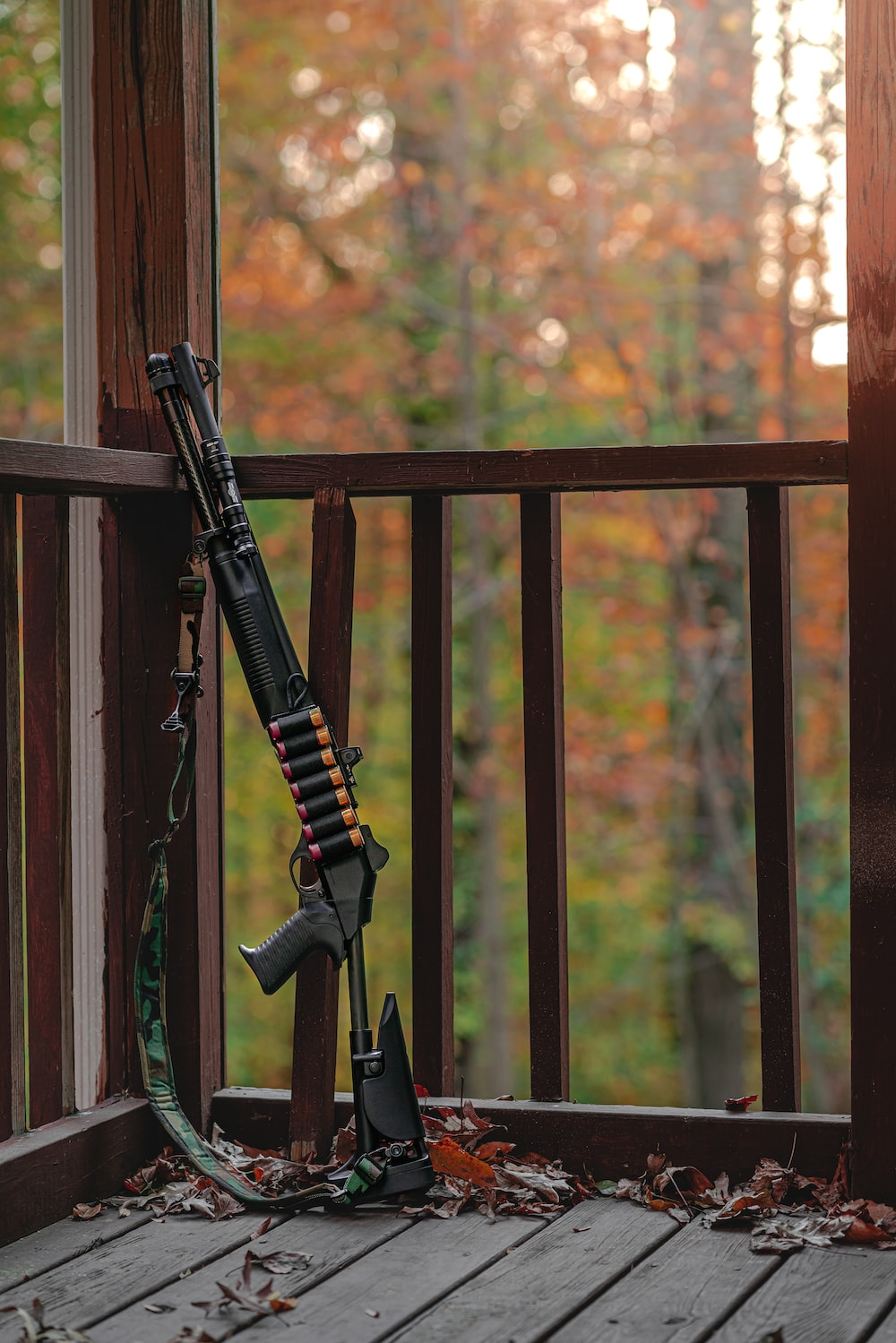 A shotgun propped against a corner of a porch