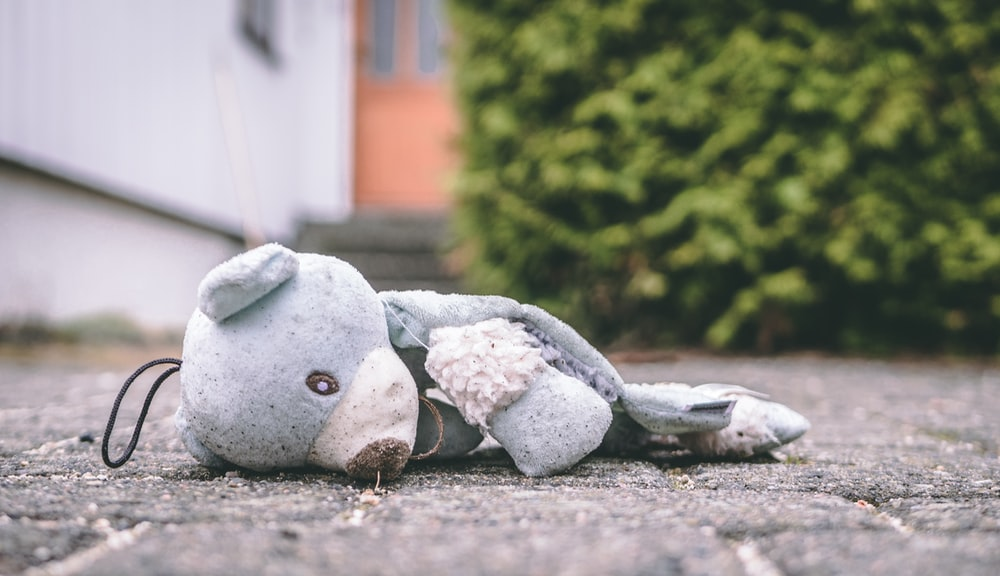 A torn teddy bear lying on the ground 