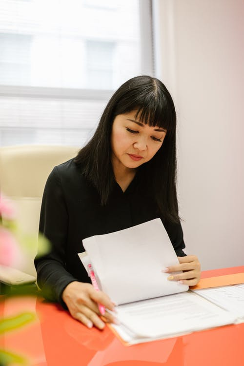 A woman sitting at a table looking through documents 